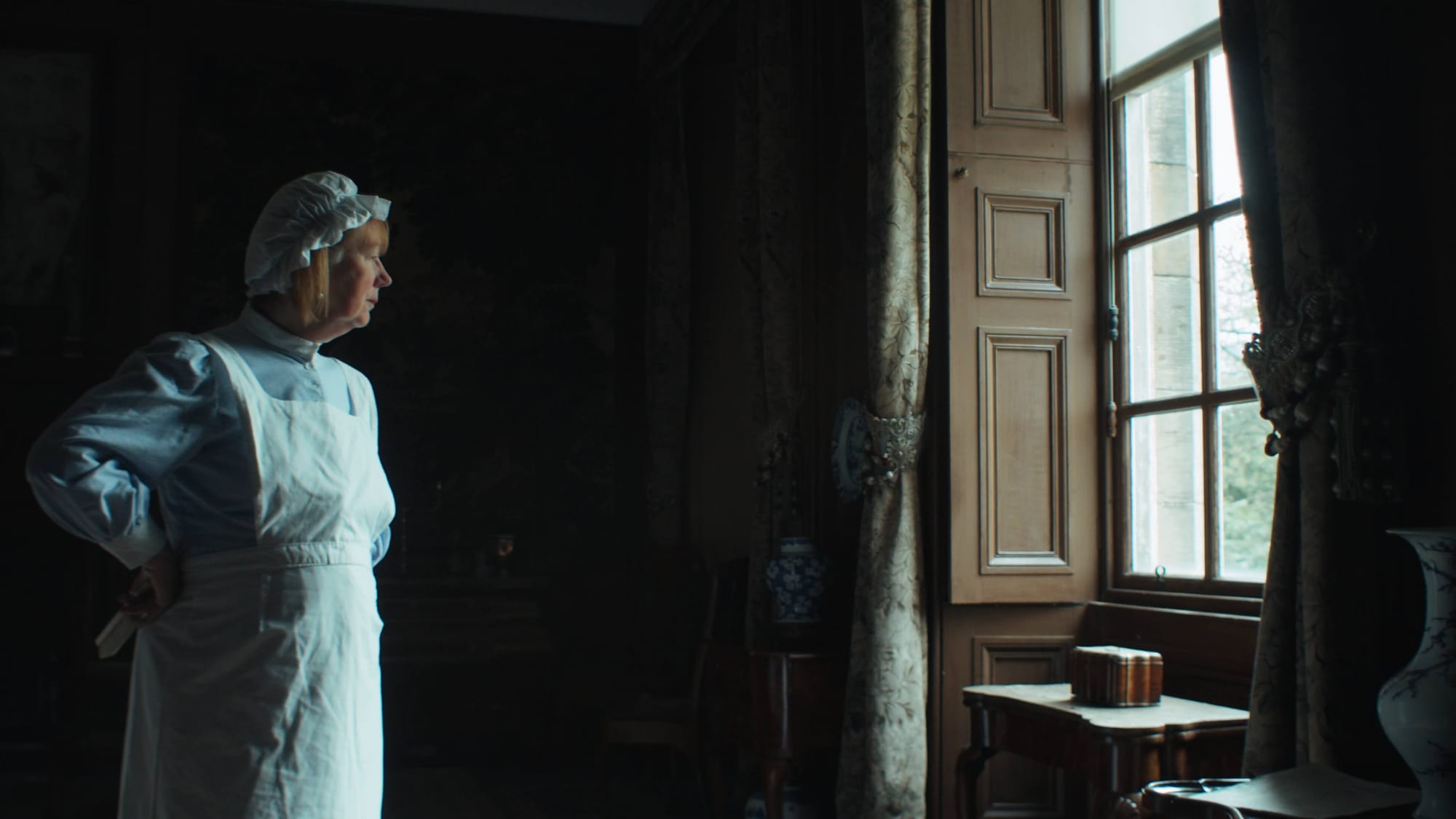 A maid at Lauriston Castle in Edinburgh looking out of the window