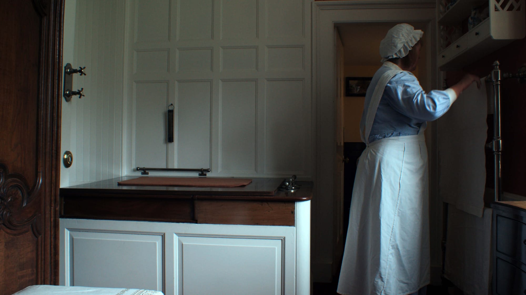 A woman dressed as a maid arranges a towel in a bathroom at Lauriston Castle in Edinburgh